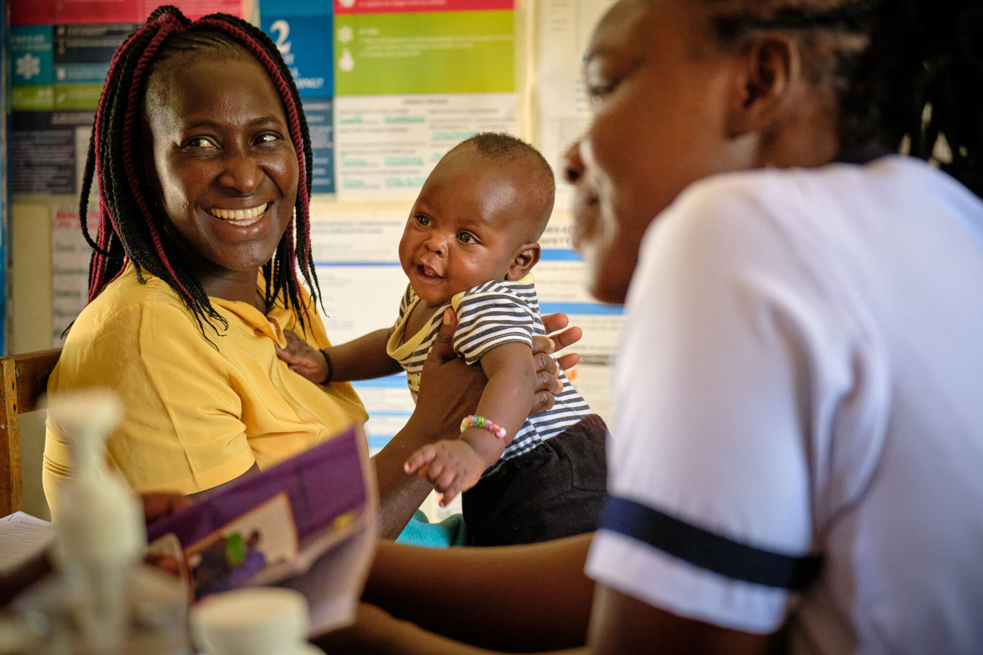 A woman holding a baby listens to a healthcare worker