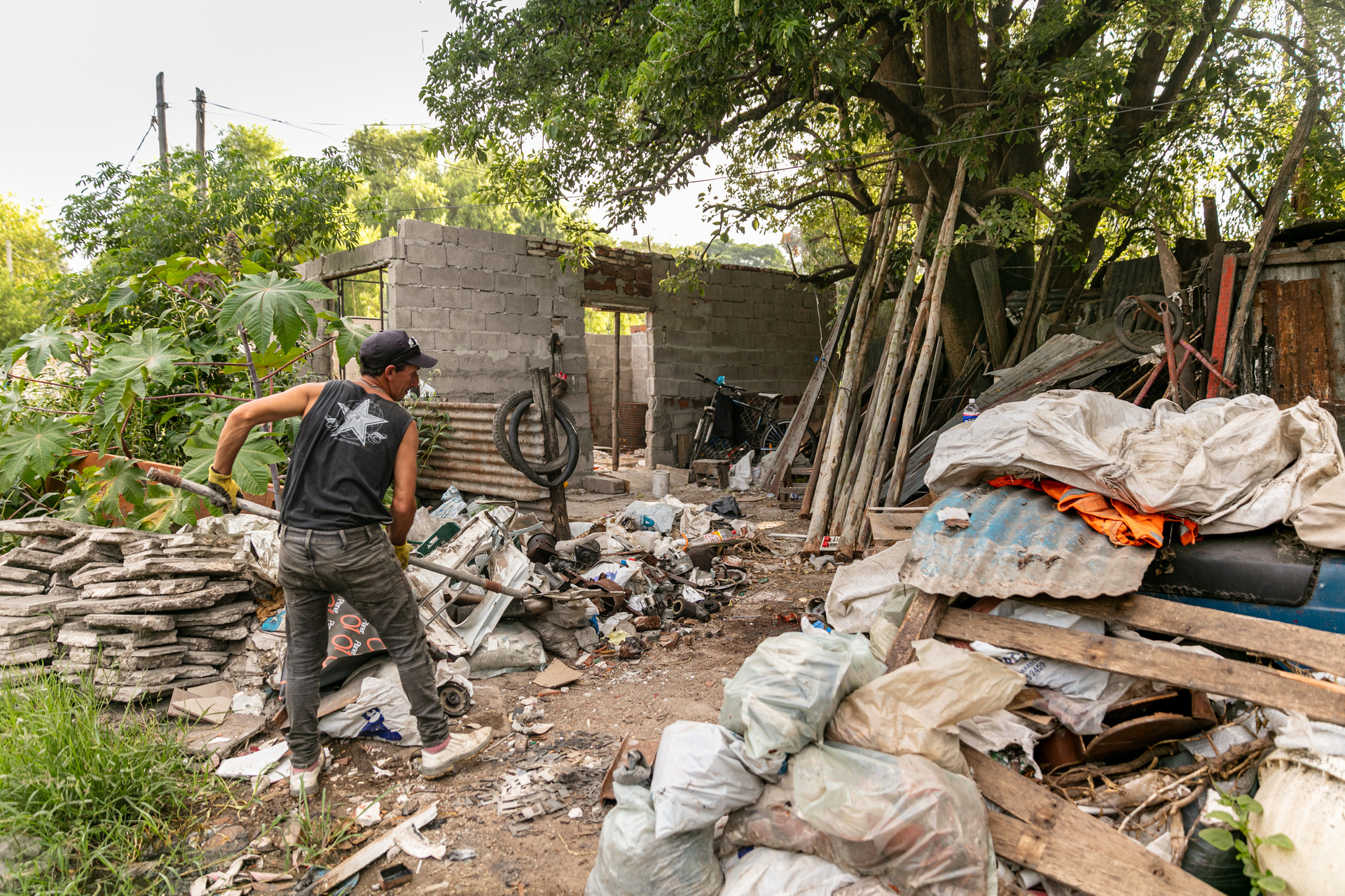 A man works in front his home that he is building across from the main garbage dump in the city