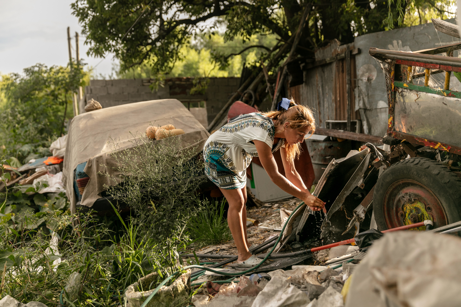 A woman washes her hands in front of her home in a settlement in a garbage dump
