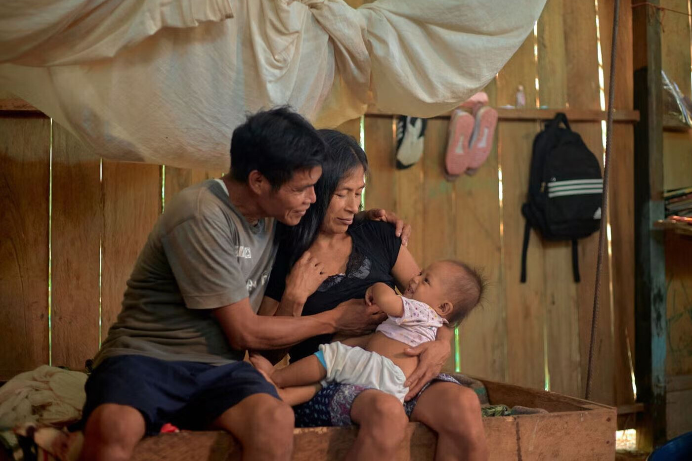 A father and mother are lovingly interacting with their baby.