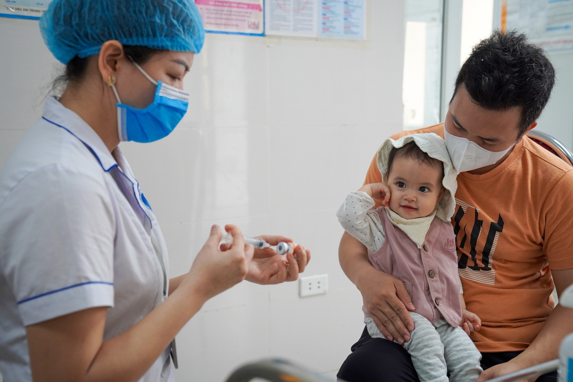 6-month-old baby girl held by a man receives a measles vaccine shot