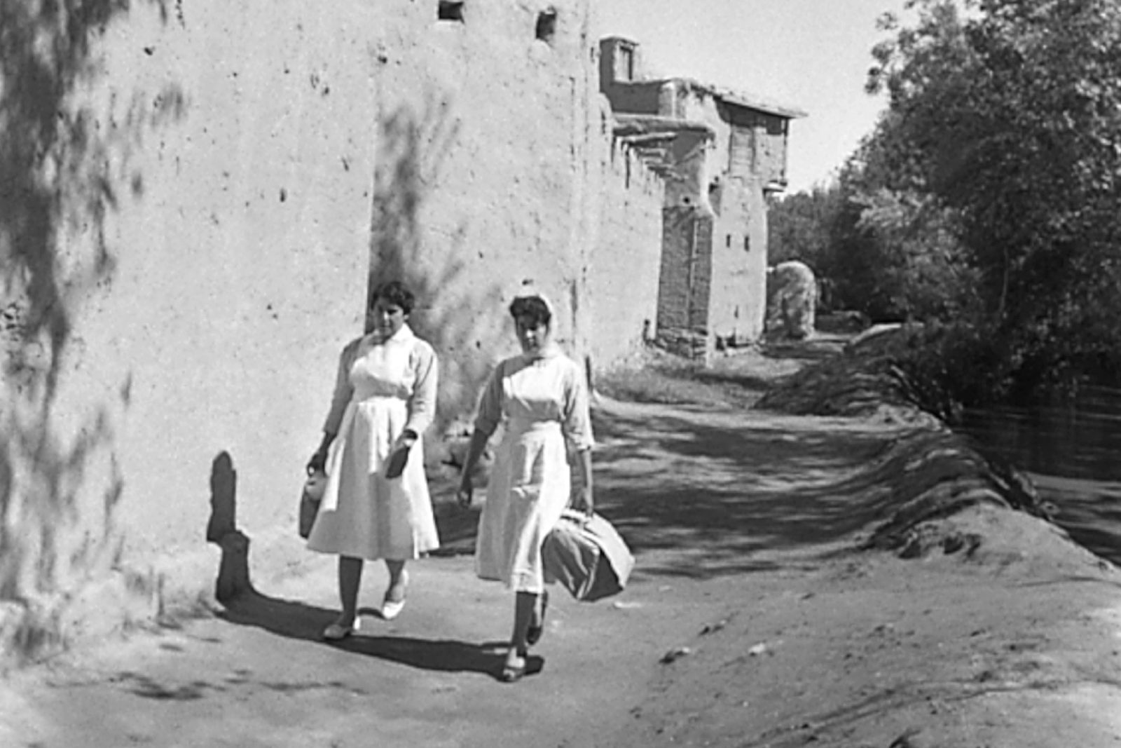 Two auxiliary nurse midwives walking down a road. A black and white photo from 1960.