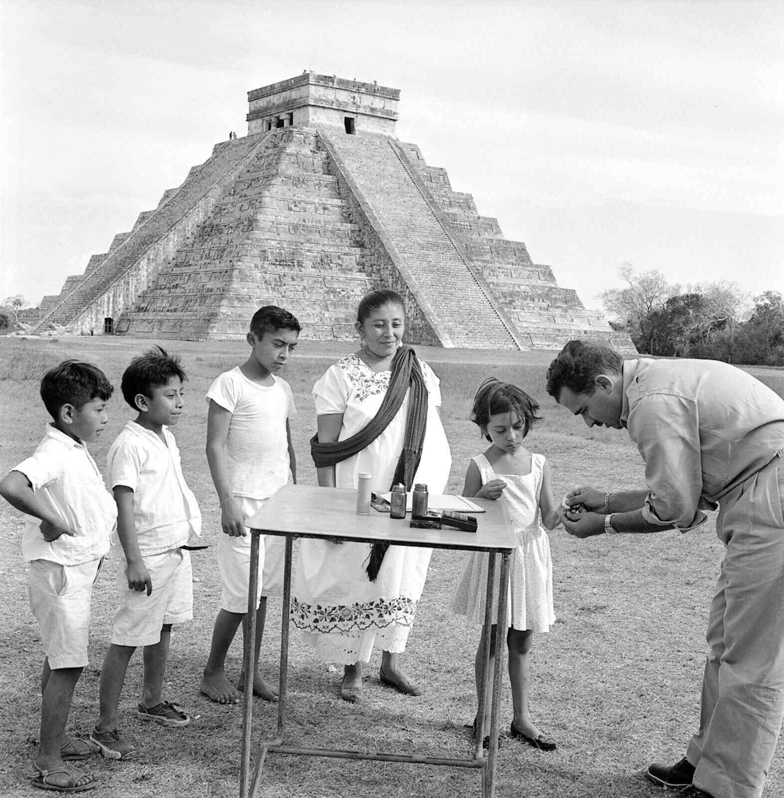 A little Mexican girl, standing in front of a Maya monument, giving sample of her blood for a test