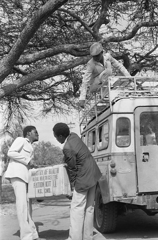 Kenya 1985: men unloading a health centre kit containing essential medicines from a truck