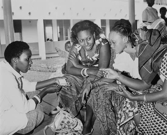 African region 1980: young African wives discuss the advantages and drawbacks of the contraceptive pill with the community health worker