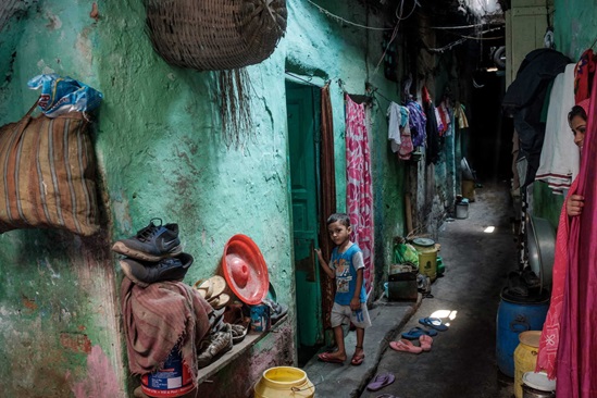 India 2019: a young boy stands outside a one-room tenement in Kolkata