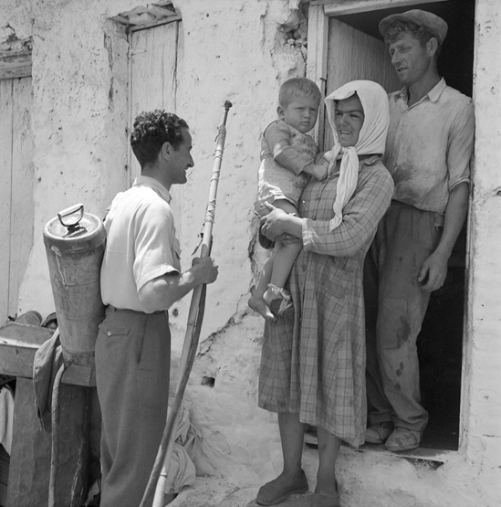Greece 1958: a family standing on their doorstep are being told that they must leave their house as the village is about to be sprayed with a special oil-and-DDT solution, as a prevention against malaria-bearing mosquitoes