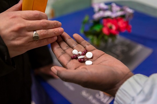 Canada 2019: a close up of hands with tablets being given by a public health nurse to a patient for treatment of his tuberculosis