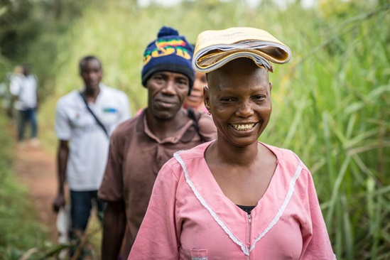 Sierra Leone: woman smiling walking along a track followed by several men