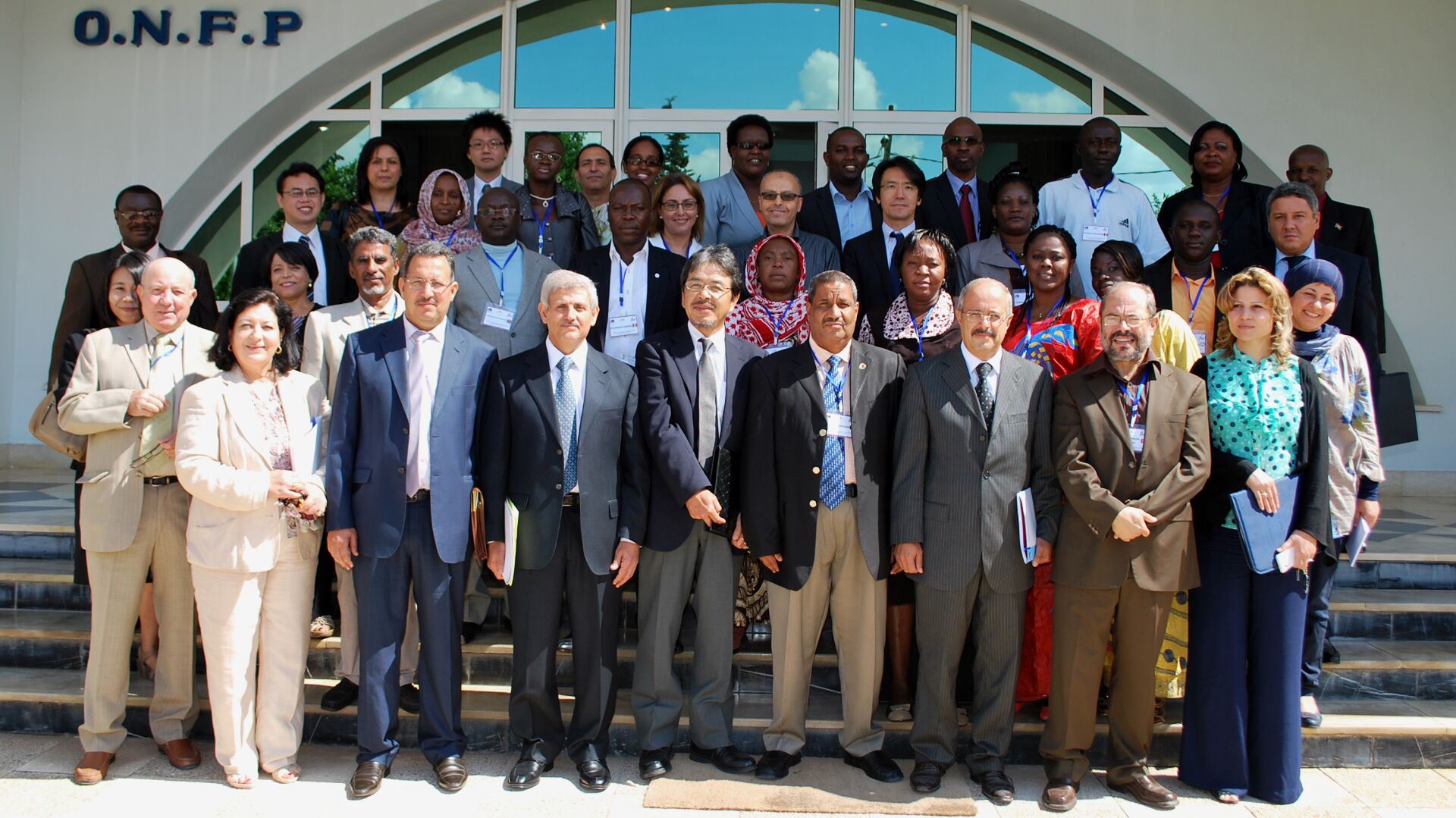 Group photo of large group of people in front of a building entrance.