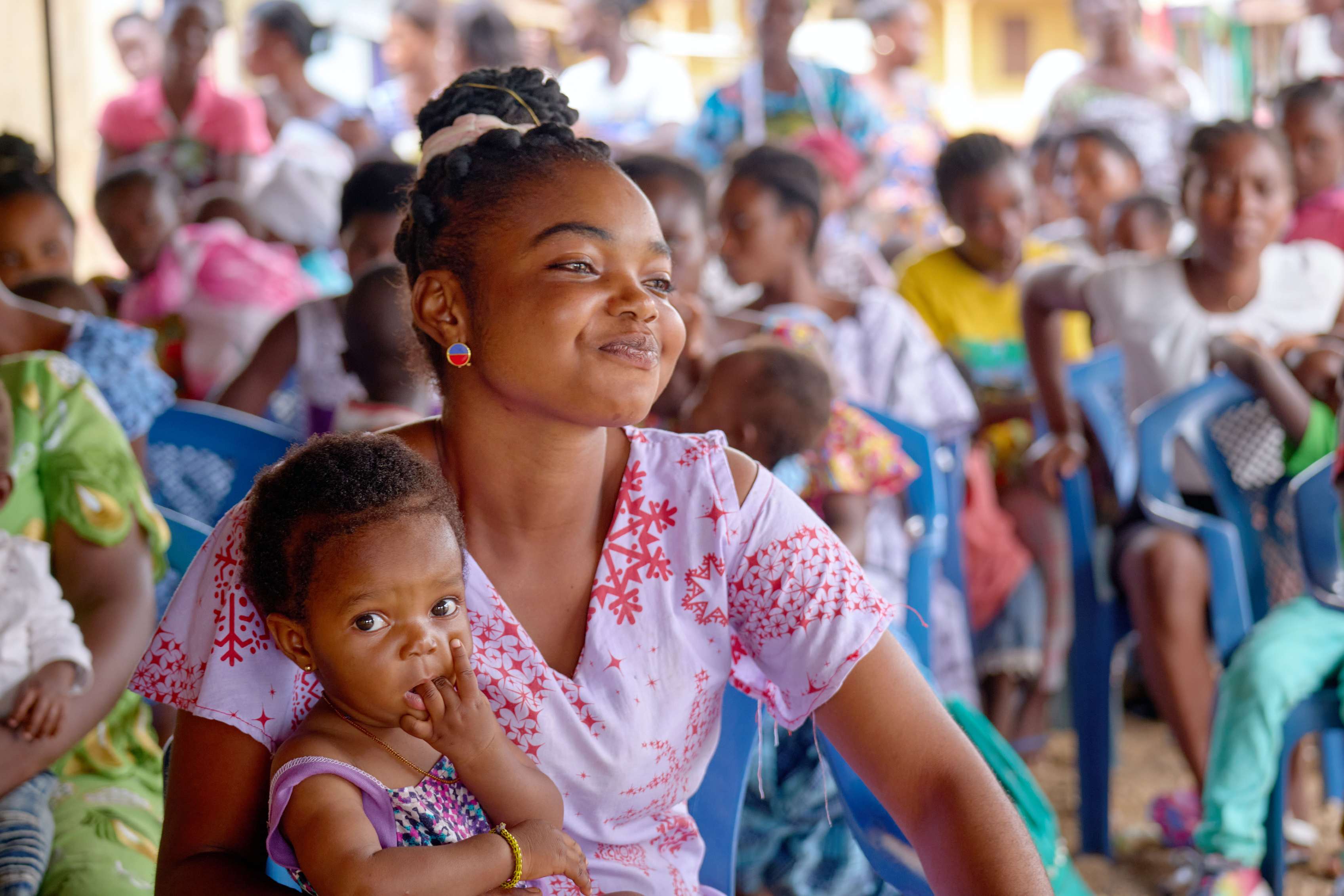 A young child sits in her mother's lap .