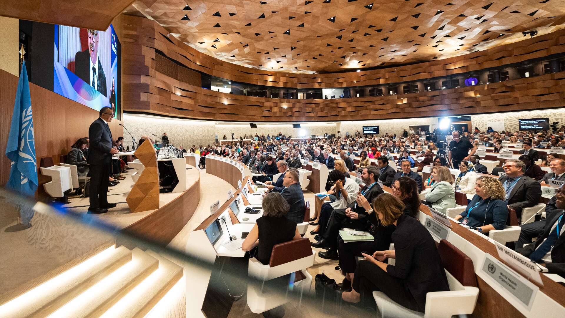 A crowded meeting room with a man standing at the podium