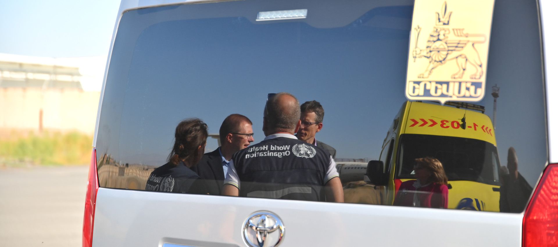 world health organization professionals standing outside an ambulance