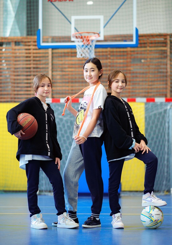 Three young girls on a basketball court.
