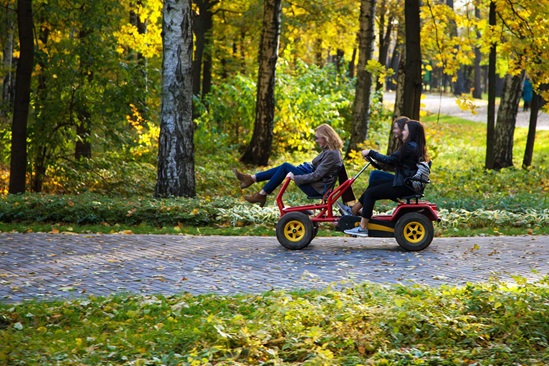 Three young women riding a fun pedal vehicle in Ostankino park, Moscow, Russia.