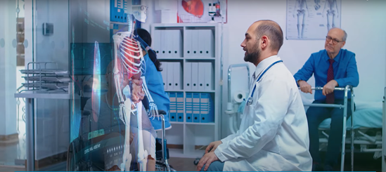 A doctor is talking to a patient in a wheelchair while looking at images of a human body on a screen